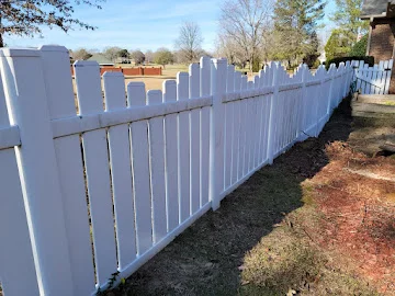 White vinyl picket fence with flat-top pickets and horizontal rails along a residential lawn edge