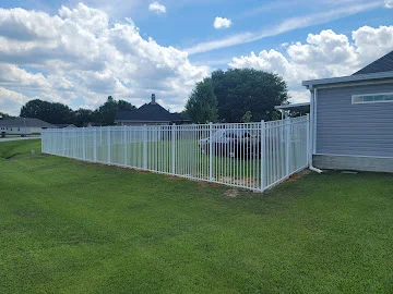 White aluminum picket fence installed along a green lawn beside a gray vinyl-sided house