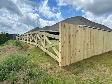 New wood privacy fence with vertical boards and open rail section with diagonal bracing on a sloped yard