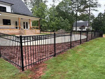 Black aluminum picket fence with curved run and brick porch, newly graded soil at base