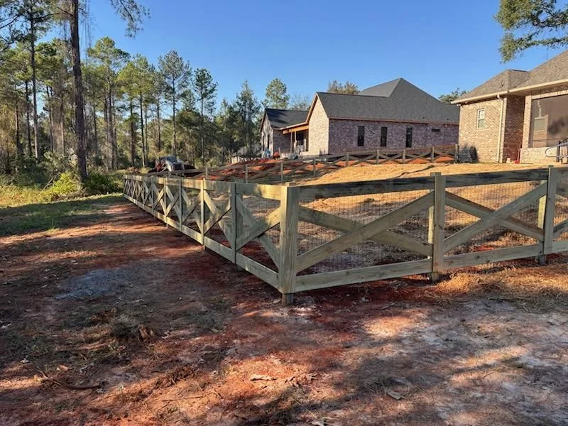 A wood privacy fence installed in the back yard of a ranch-style home in Cochran, Georgia, with a wide open lot and Georgia pine trees visible at the property edge.
