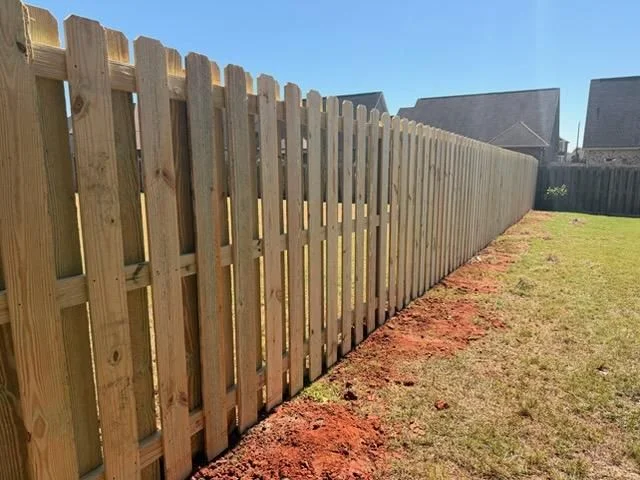 A chain link fence running along the perimeter of a rural Peach County property near Fort Valley, with open pasture land and Georgia pines visible beyond the fence line.