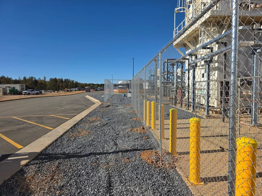 A chain link perimeter fence surrounding a light industrial property on Industrial Boulevard in Hawkinsville, GA, with a sliding gate at the entrance and open sky above.