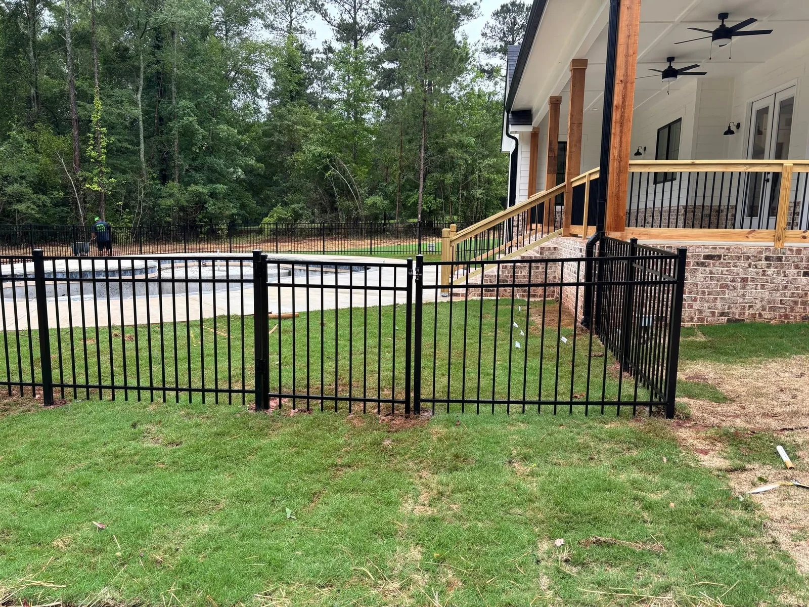 A newly installed residential privacy fence along the backyard of a single-family home in Warner Robins, Georgia, with green grass and a clear blue Middle Georgia sky in the background. The fence posts are set straight and level, showing clean, finished craftsmanship typical of a Houston County residential installation.